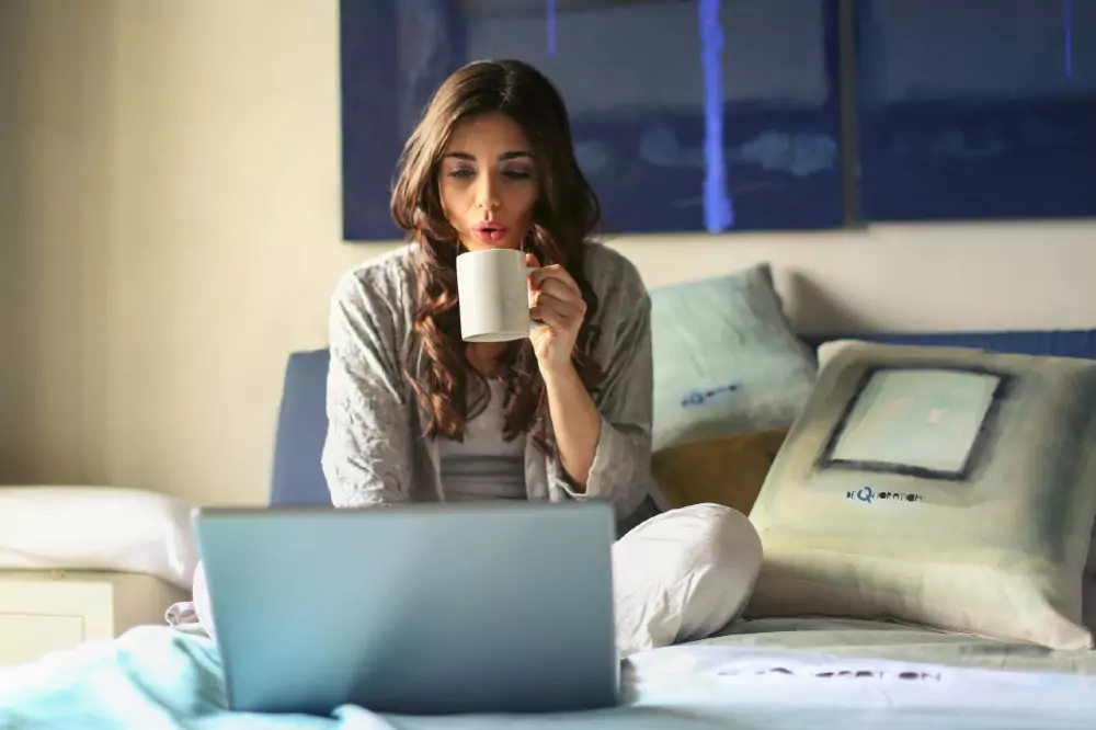 A woman drinking coffee and using her laptop