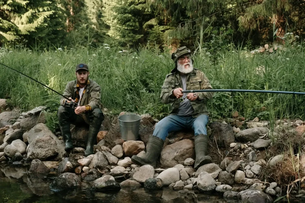 Two men fishing in a lake surrounded by a forest.
