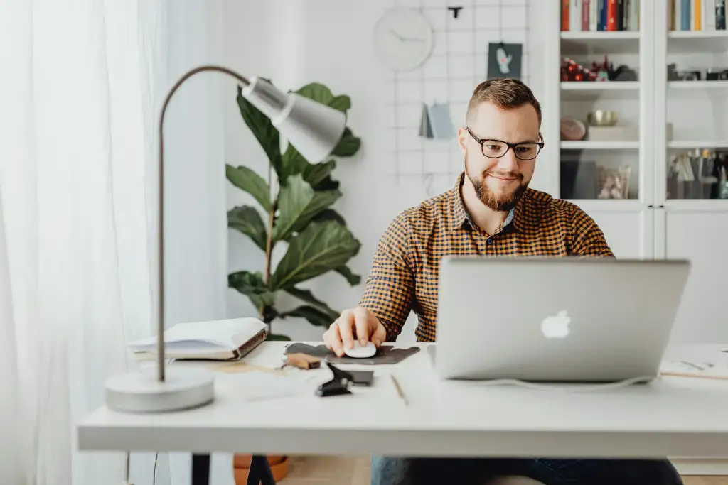 A man on his laptop at a well-organized home office desk.