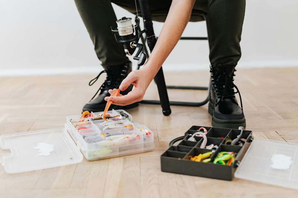 A person organizing fishing tackle boxes filled with colorful lures and bait.