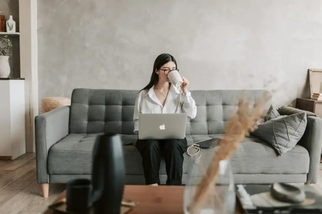 A guest enjoys coffee while working on a laptop in a cozy vacation rental living room.