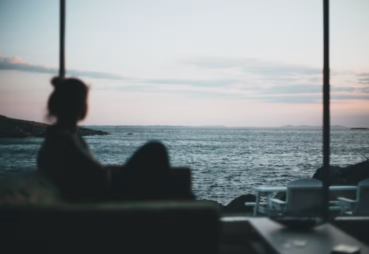 Silhouette of a person sitting near the beach during sunset