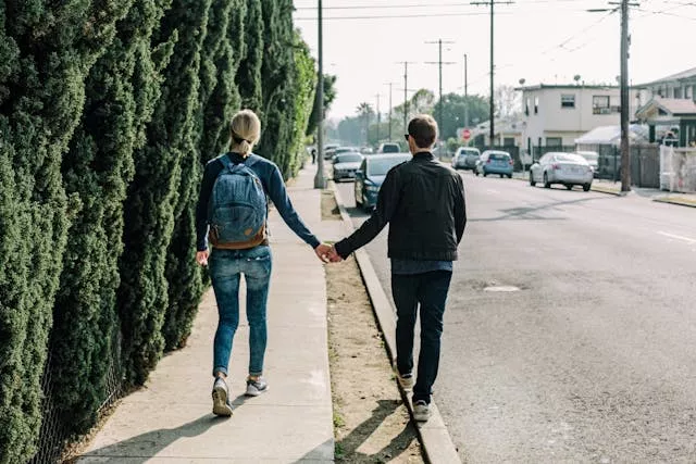 A couple holding hands walking down a sidewalk