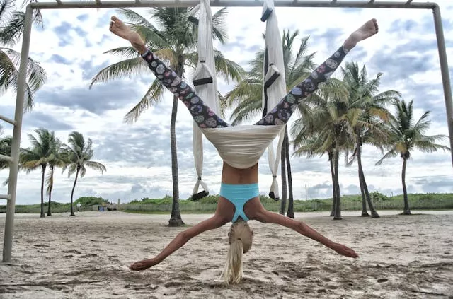 person performing aerial yoga on a beach